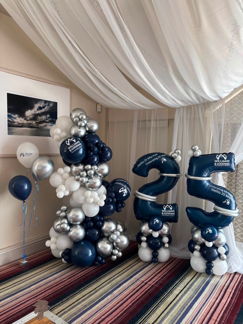 Navy and silver balloon columns with giant 25 numbers, branded with the company logo
