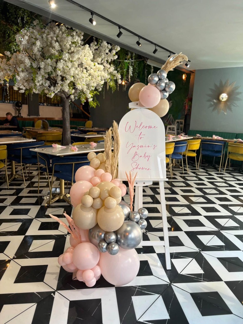 Blush pink, gold and silver balloons around a welcome sign for a baby shower