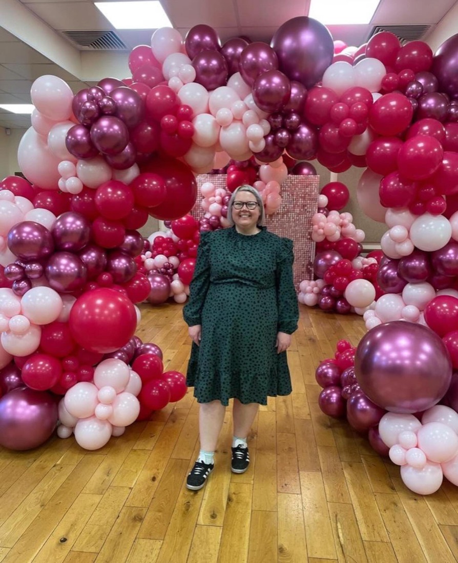 Amy standing in front of a huge pink, berry and chrome balloon wall